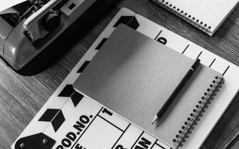 Clapper board and vintage typewriter at wooden desk table